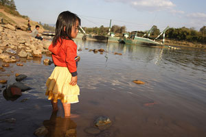 Photo of a young girl paddling at the edge of a river