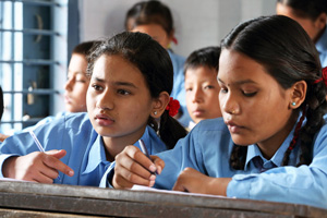Two girls at a desk in a classroom