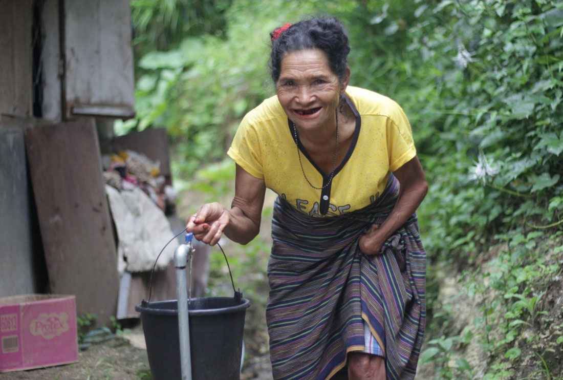 Grandma Ne fetching water with a bucket