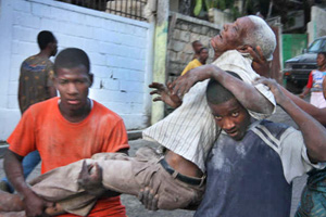 Photo of two men carrying an older injured man along a street