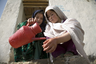 two afghan girls washing their hands