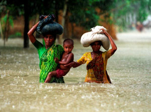 Two Bangladeshi women carrying food supplies through floodwaters