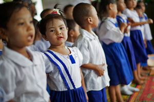 Young children in school uniform standing in a line, shoulder to shoulder