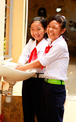 Two Vietnamese schoolgirls washing their hands