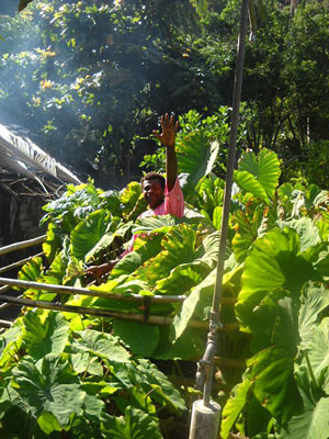 Photo of Bani smiling and waving from his garden.