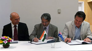 Three men at desk signing papers