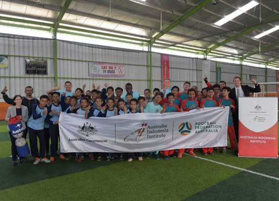 Group photo of soccer players holding a sign with logo's on it.