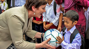 Senator Stephens handing soccer ball to young boy