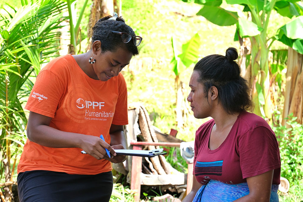 Photo of two women, one taking details of the other on a clipboard.