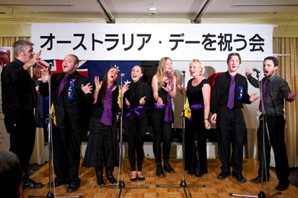 group of singers in front of a banner written in Japanese