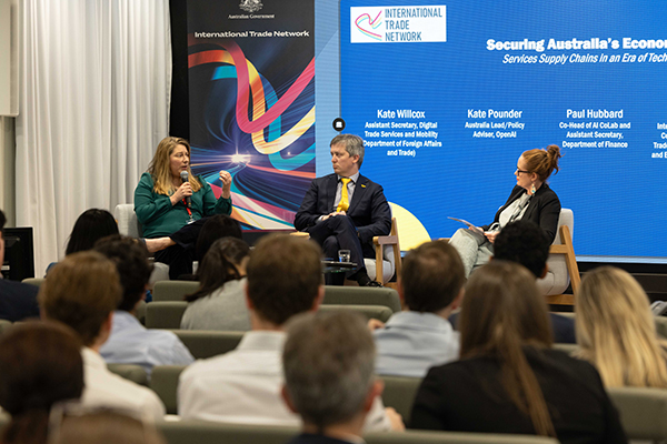 Panel discussion at an International Trade Network event, with three speakers seated on stage and a large screen behind them displaying the session title on Australia’s economic future, while an audience listens in the foreground.