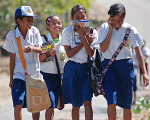 Photo of four laughing girls in school uniform walking along a road.