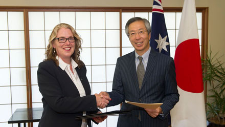 Jan Adams and Yoshitaka Akimoto exchange notes and shake hands.