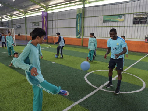 Photo of two people kicking a soccer ball to each other.