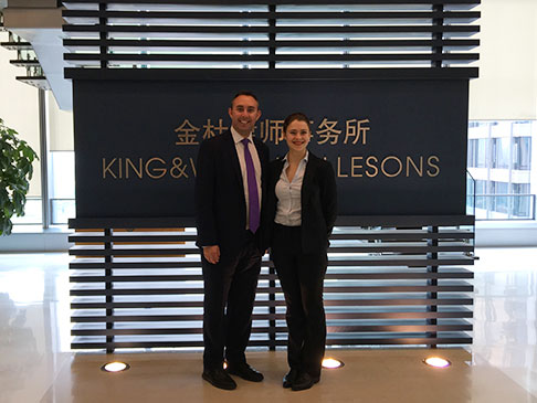 Two people standing in front of a King & Wood Mallesons sign.