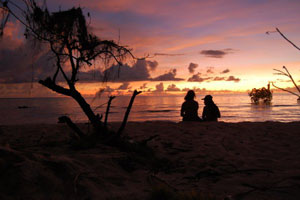 Photo of two people watching a beautiful sunset on the beach
