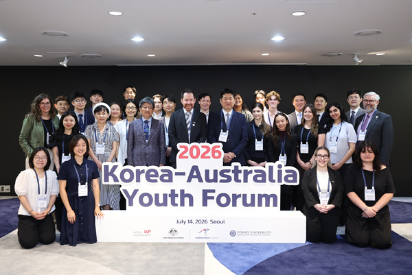 A formal photo of a group of 30 people standing in rows around a large sign that reads 2026 Korea-Australia Youth Forum.