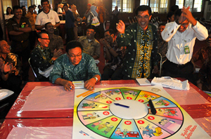 People playing board game with people watching and clapping