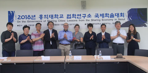group of people standing around a table holding their hands together to their chest