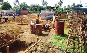 Wall of concrete blocks partially constructed, with frame laying on top waiting to be erected.