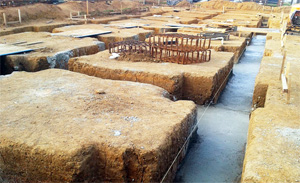 Wall of concrete blocks partially constructed, with frame laying on top waiting to be erected.