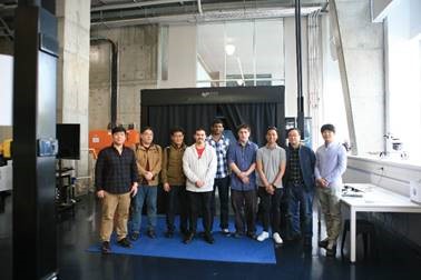Group of men standing in front of large machinery in a workshop