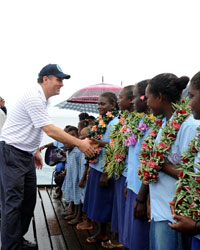 Photo of a man shaking hands with a group of children