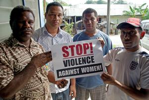 Four men holding a sign that says 'Stop violence against women' 