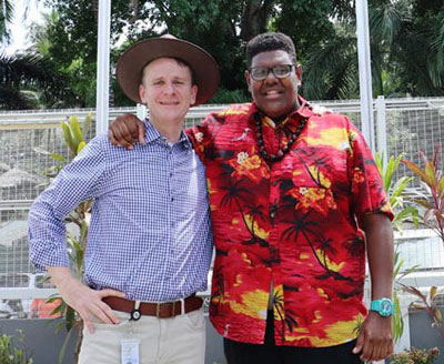 Photo of two men wraping their arm around each others shoulders and smiling.