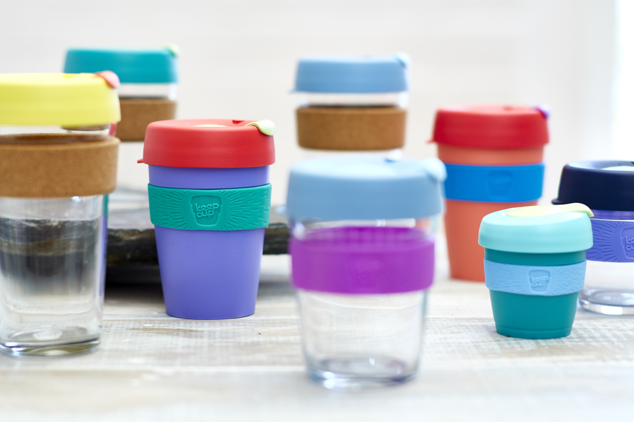 Various styles of coloured KeepCups placed in rows