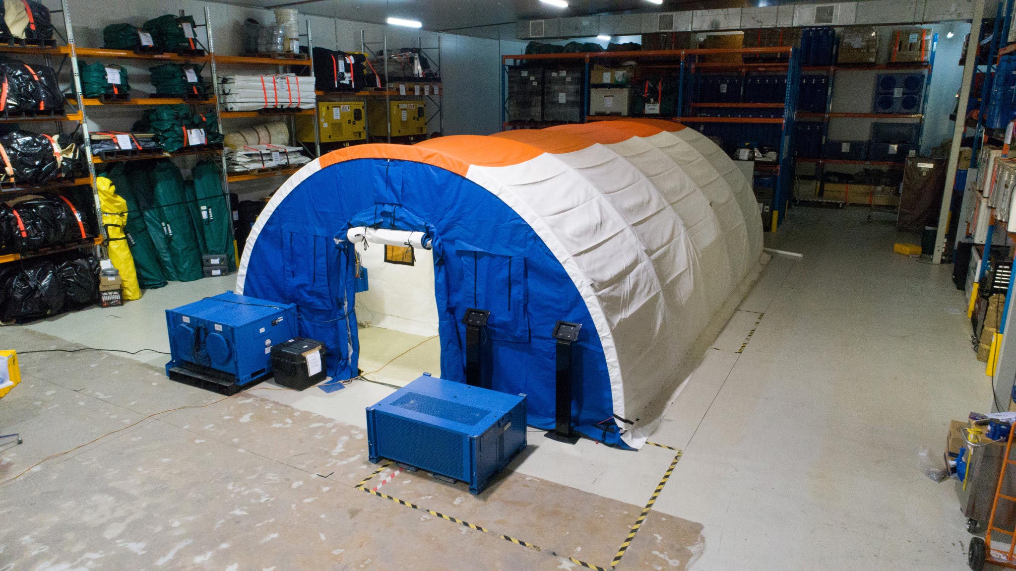 A disaster zone operating theatre tent, set up indoors in a storage facility