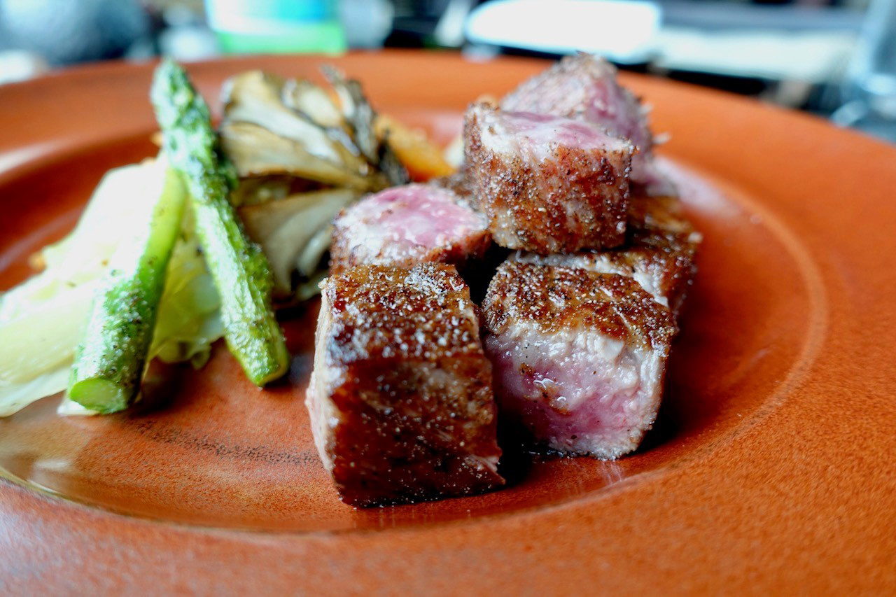 Cooked beef on a plate with green asparagus spears