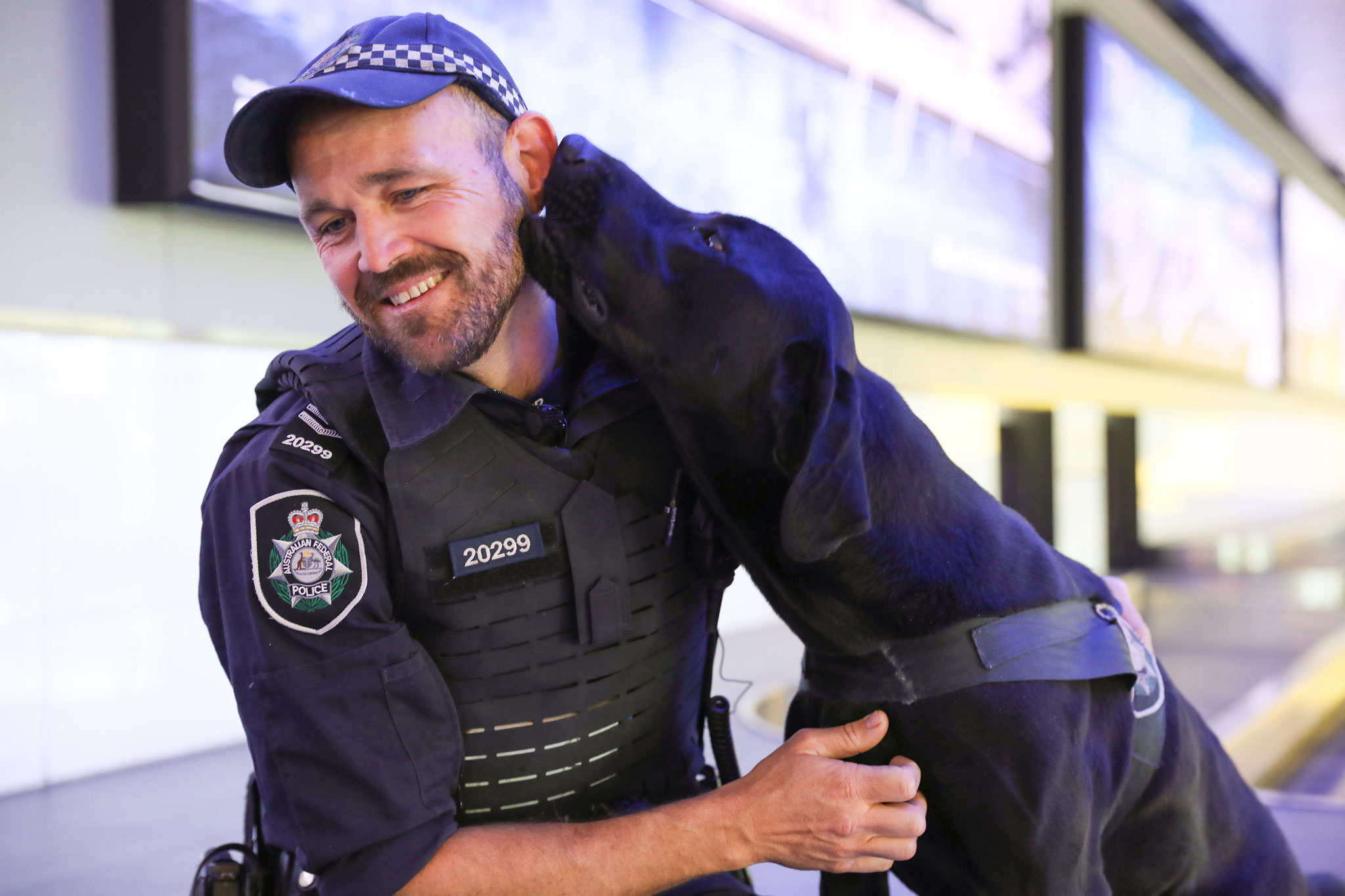 Mathew Blow being licked by black labrador sniffer dog Leo