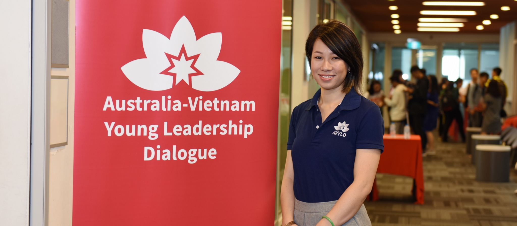 Thao Nguyen, standing with red Australia – Vietnam Young Leadership Dialogue banner behind her