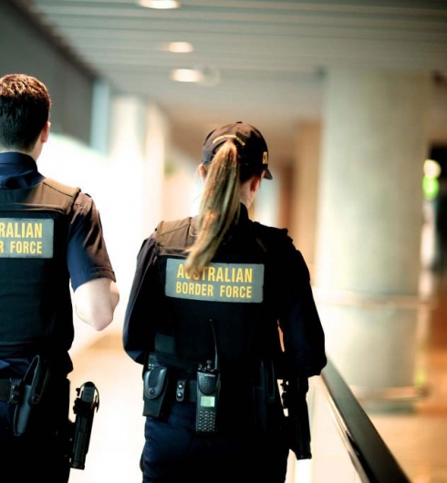The backs of two Australian Border Force operatives walking in an airport