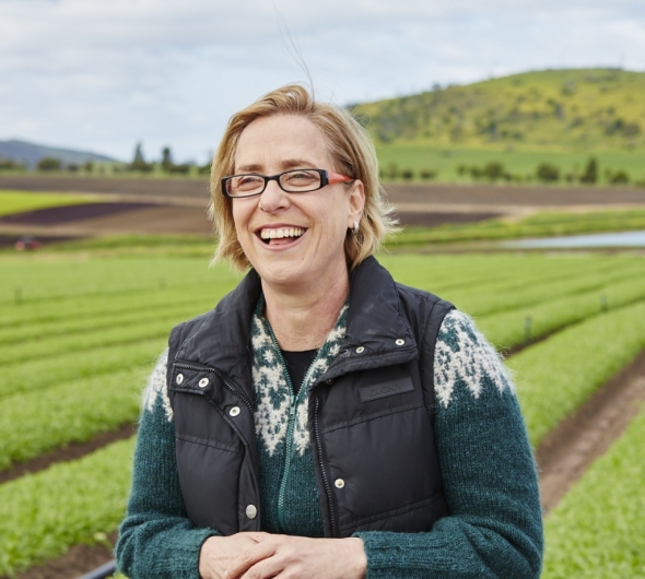 Headshot of Ros Harvey with a field and green hill and trees in background