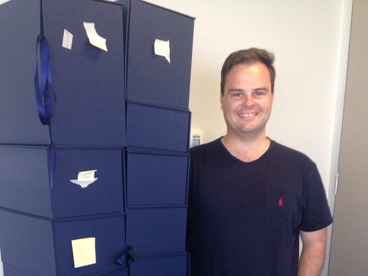 DFAT officer Hugh Boylan standing next to boxes containing the final text of the Trans Pacific Partnership agreement. [DFAT]