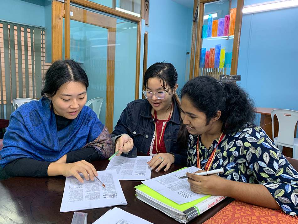 Jasmine tutoring two students, at a desk with workbooks