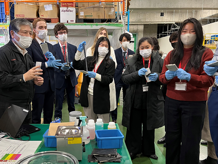 Scholars wearing masks and blue gloves and red lanyards, posing with various artefacts related to the disaster recovery mechanisms