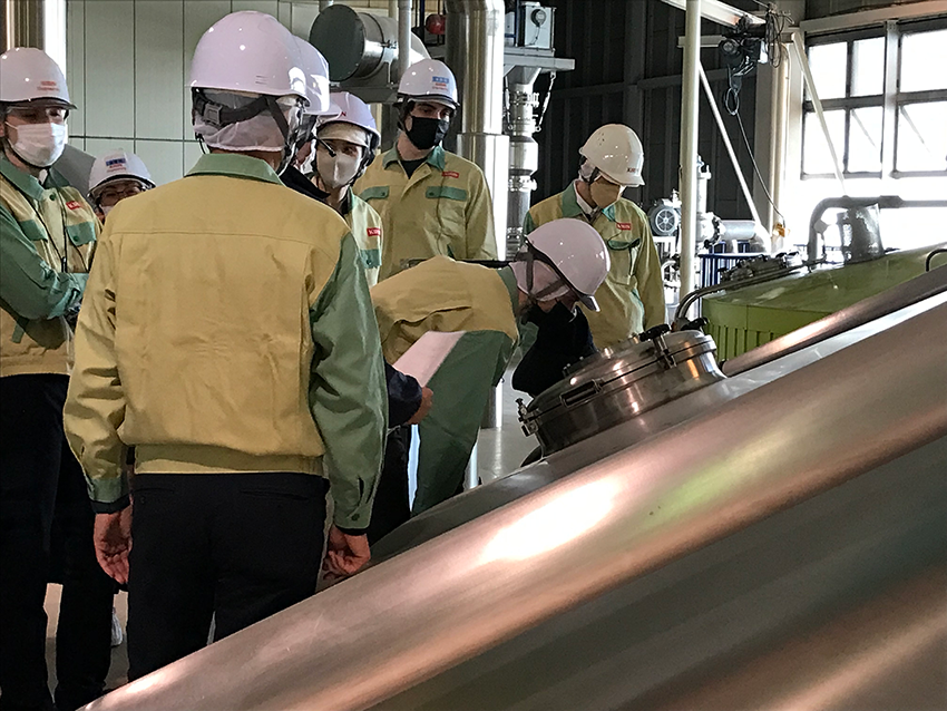 Group of people gathered in his vis jackets and helmets, inspecting brewery