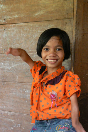 Photo of Olieria, a child with disability, waving to camera for photo.