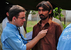 Photo of a doctor holding his stethoscope against the chest of a male patient