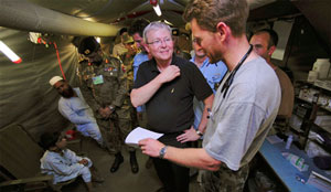 Photo of Kevin Rudd talking with a member of the Medical Task Force inside the temporary health facility, with Pakistani military and patients in the background