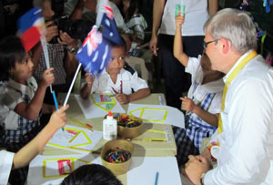 Photo of Foreign Minister Kevin Rudd with Aussie flags and a group of children