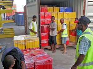 Photo of six New Guinea male workers unloading plastic crates containing books from a shipping container
