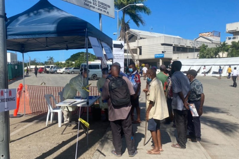 Photo of several locals queuing on the street to undertake initial screening for COVID-19.