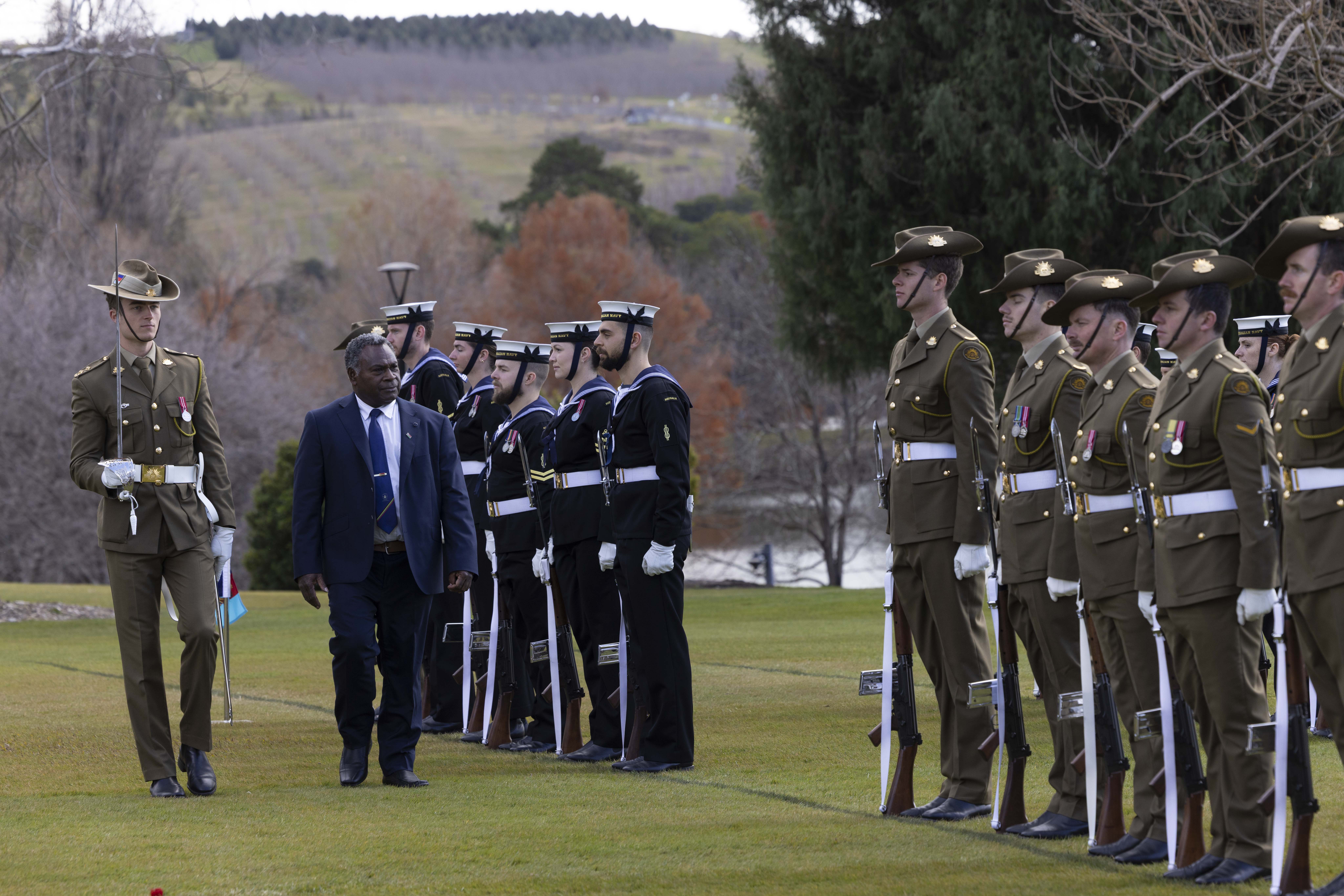 His Excellency Mr Jimmy Nipo walking past a line of Australian soldiers. 