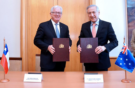 Minister Robb with Chile's Foreign Minister, Heraldo Muñoz holding up brown leather folders