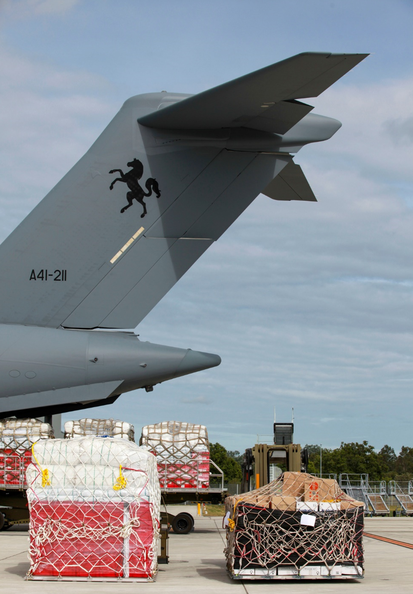 Image shows the end of a plane with crates of emergency relief supplies in the foreground