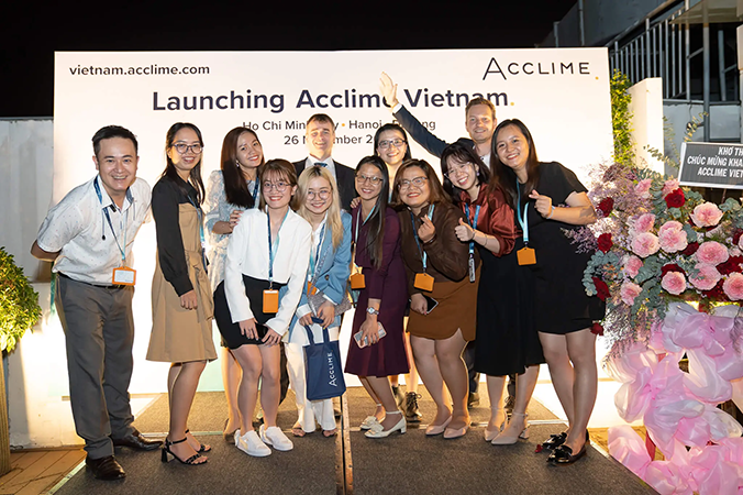 A group of twelve people standing in front of a sign which reads Launching Acclime Vietnam.